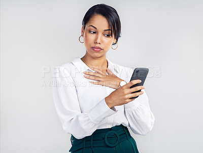 Buy stock photo Studio shot of a young businesswoman using a smartphone and looking unsure against a grey background