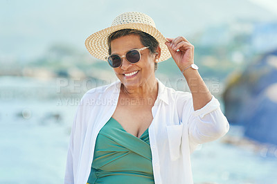 Buy stock photo Shot of an attractive mature woman standing alone during a day out on the beach
