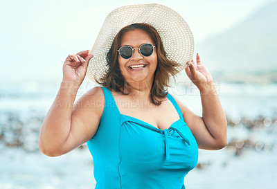 Buy stock photo Shot of an attractive mature woman standing alone during a day out on the beach