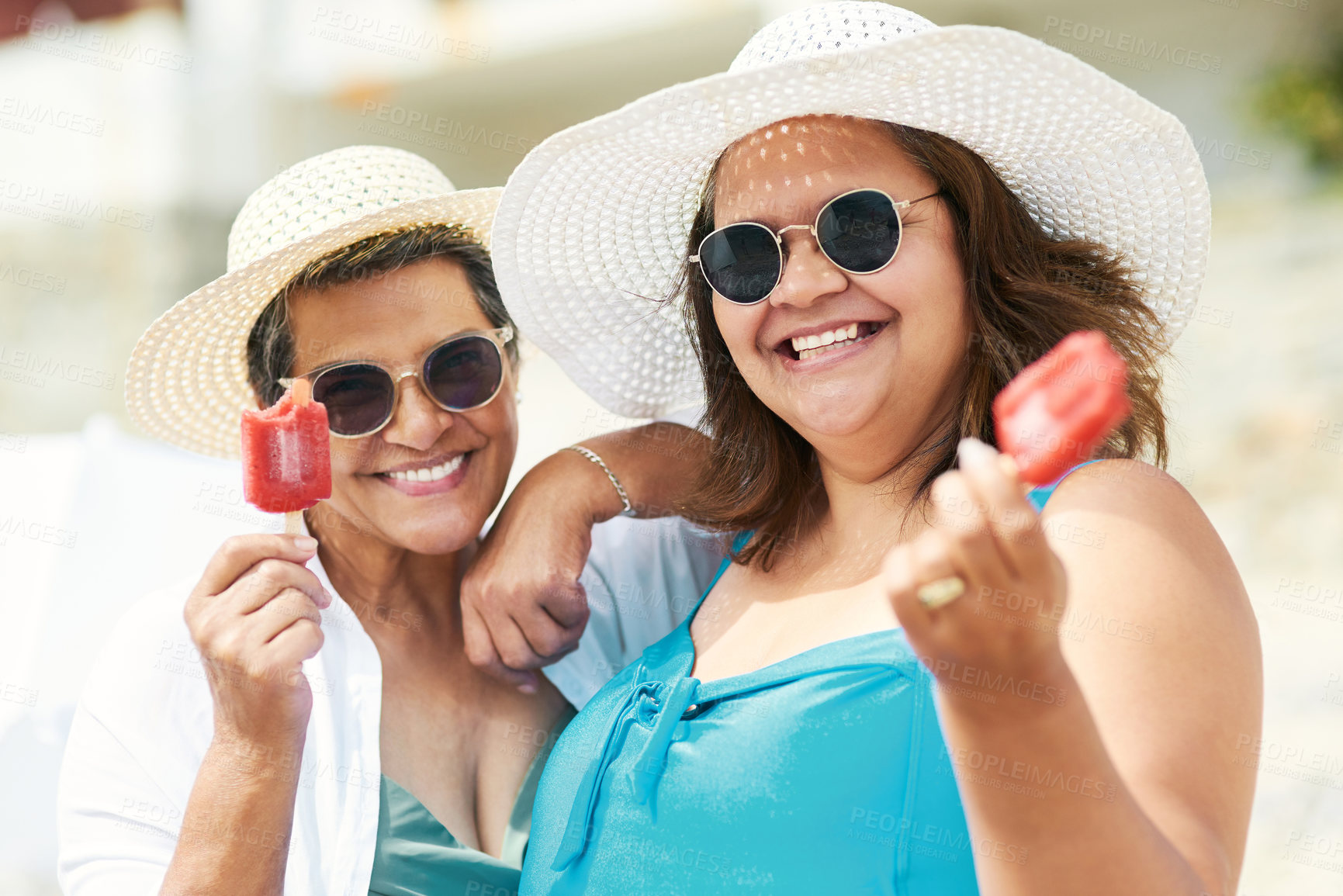 Buy stock photo Shot of two mature friends standing together and enjoying ice cream while bonding on the beach during the day