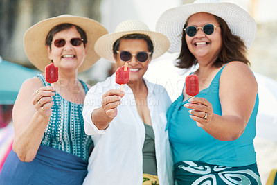 Buy stock photo Shot of a mature group of friends standing together and enjoying ice cream while bonding on the beach