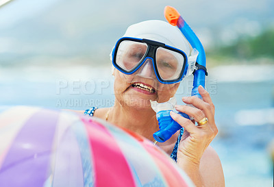Buy stock photo Shot of a mature woman wearing snorkel gear and holding an inflatable ball during a day on the beach