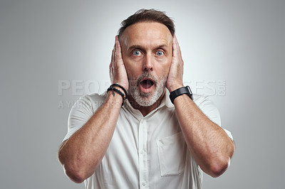Buy stock photo Studio portrait of a mature man covering his ears and looking shocked against a grey background
