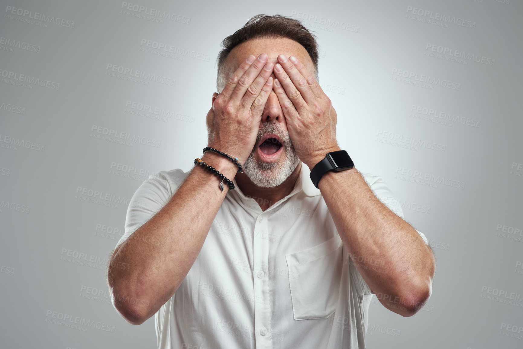 Buy stock photo Studio shot of a mature man covering his eyes and looking shocked against a grey background