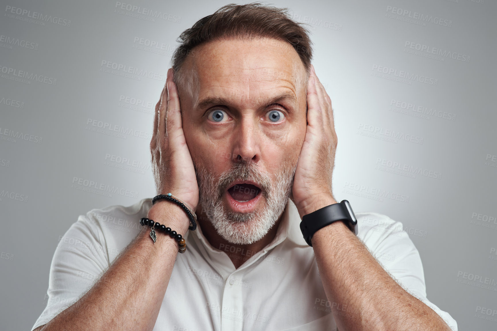 Buy stock photo Studio portrait of a mature man covering his ears and looking shocked against a grey background