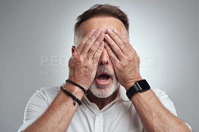 Buy stock photo Studio shot of a mature man covering his eyes and looking shocked against a grey background