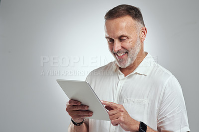 Buy stock photo Studio shot of a mature man using a digital tablet against a grey background