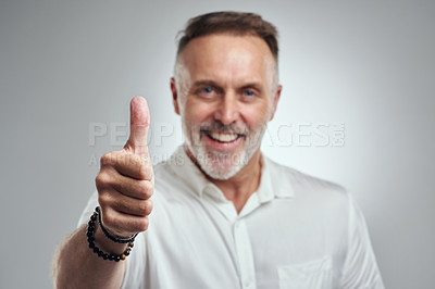 Buy stock photo Studio portrait of a mature man showing thumbs up against a grey background