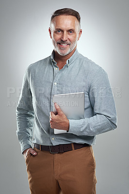 Buy stock photo Studio portrait of a mature man holding a digital tablet against a grey background