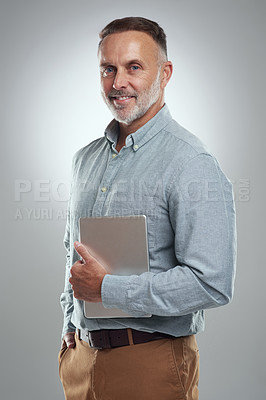Buy stock photo Studio portrait of a mature man holding a digital tablet against a grey background