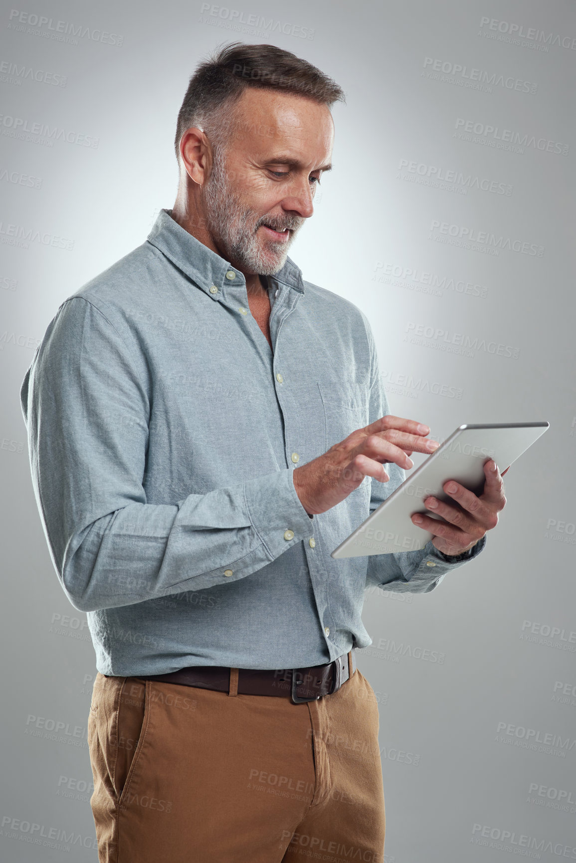 Buy stock photo Studio shot of a mature man using a digital tablet against a grey background