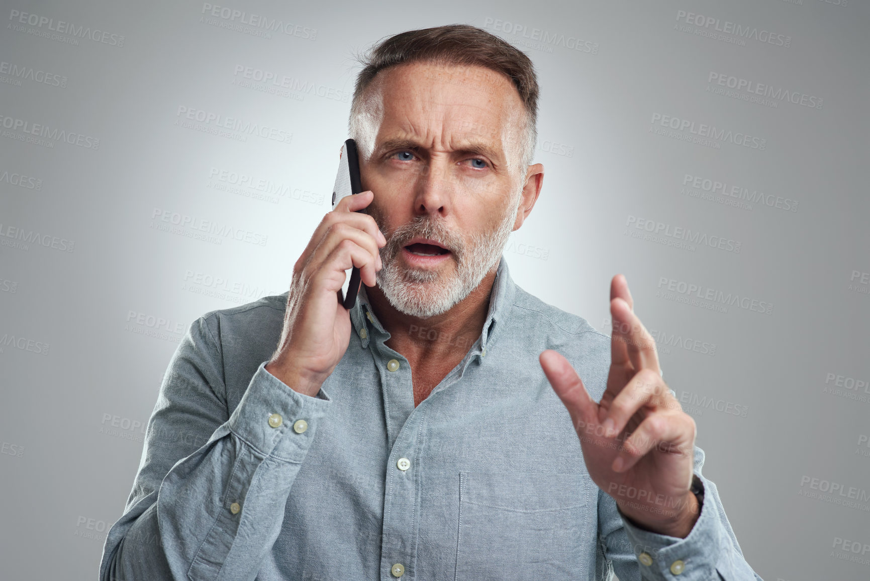Buy stock photo Studio shot of a mature man looking confused while talking on a cellphone against a grey background
