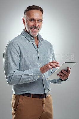 Buy stock photo Studio portrait of a mature man using a digital tablet against a grey background