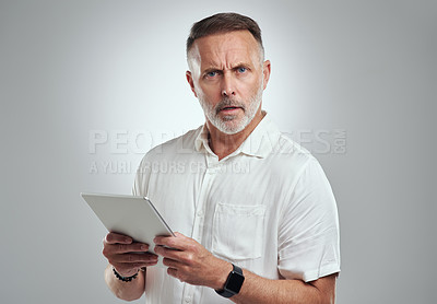 Buy stock photo Studio portrait of a mature man looking confused while using a digital tablet against a grey background