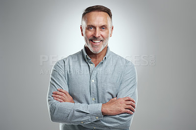 Buy stock photo Studio portrait of a mature man standing with his arms folded against a grey background