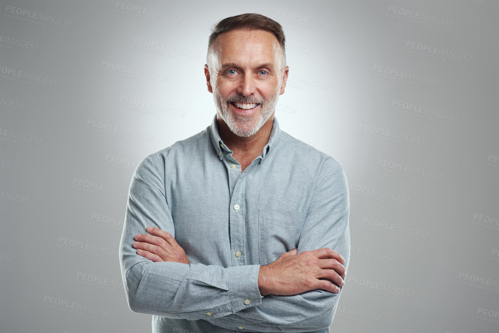 Buy stock photo Studio portrait of a mature man standing with his arms folded against a grey background