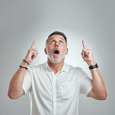 Buy stock photo Studio shot of a mature man pointing to copyspace against a grey background