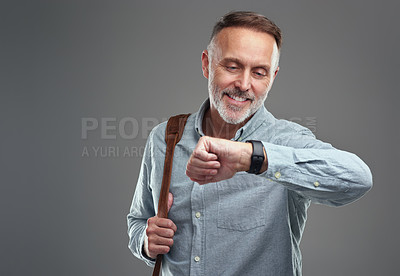 Buy stock photo Studio shot of a mature man carrying a bag and checking the time on his wristwatch against a grey background