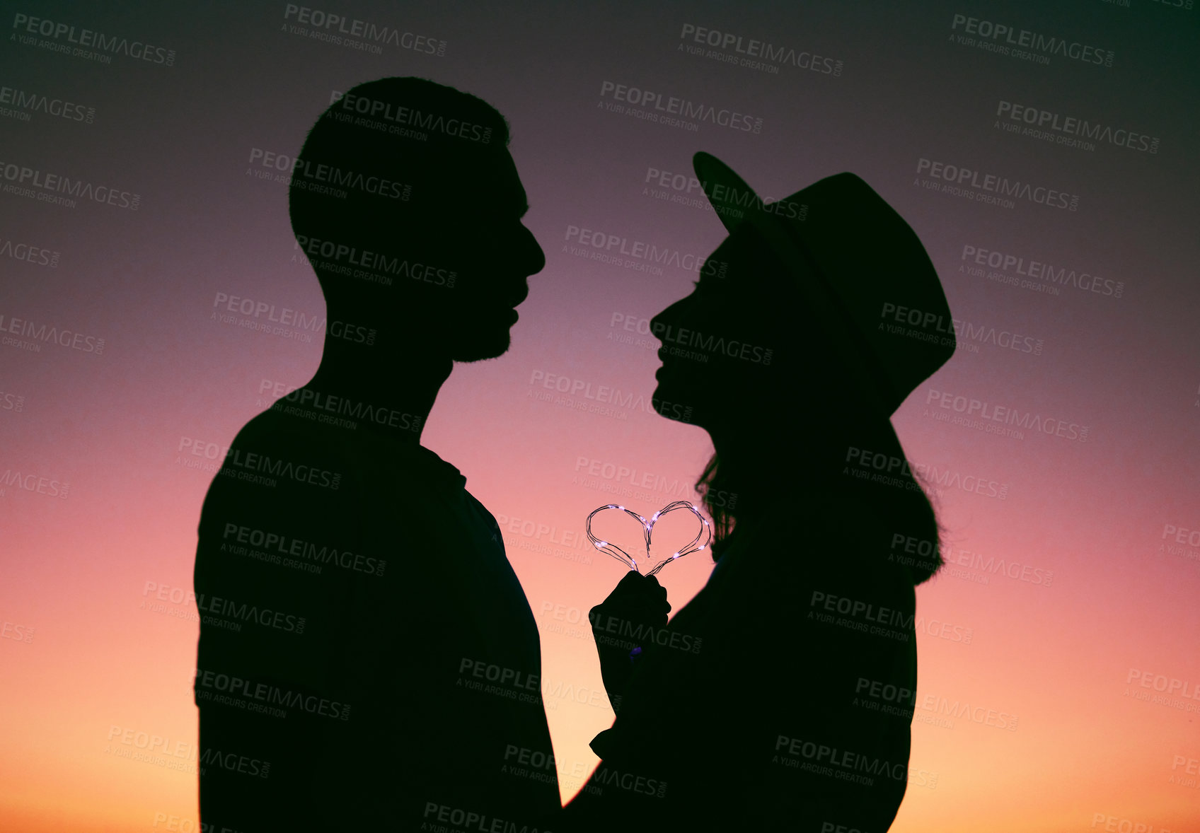 Buy stock photo Cropped shot of an affectionate young couple silhouetted at sunset