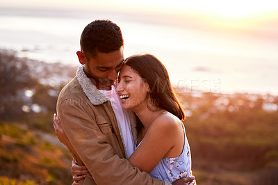 Buy stock photo Cropped shot of an affectionate young couple embracing lovingly at sunset