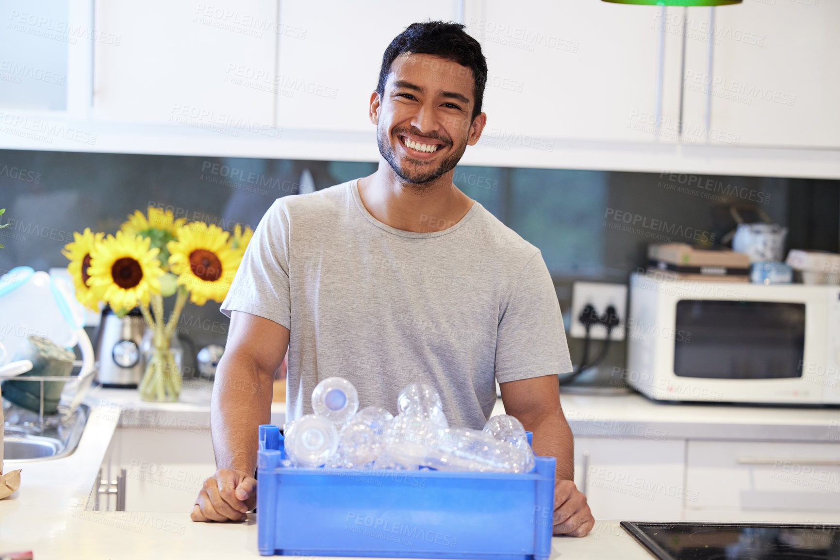 Buy stock photo Shot of a young man getting ready to recycle some bottles at home