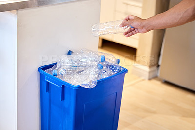 Buy stock photo Cropped shot of a man putting a bottle in the recycling bin at home