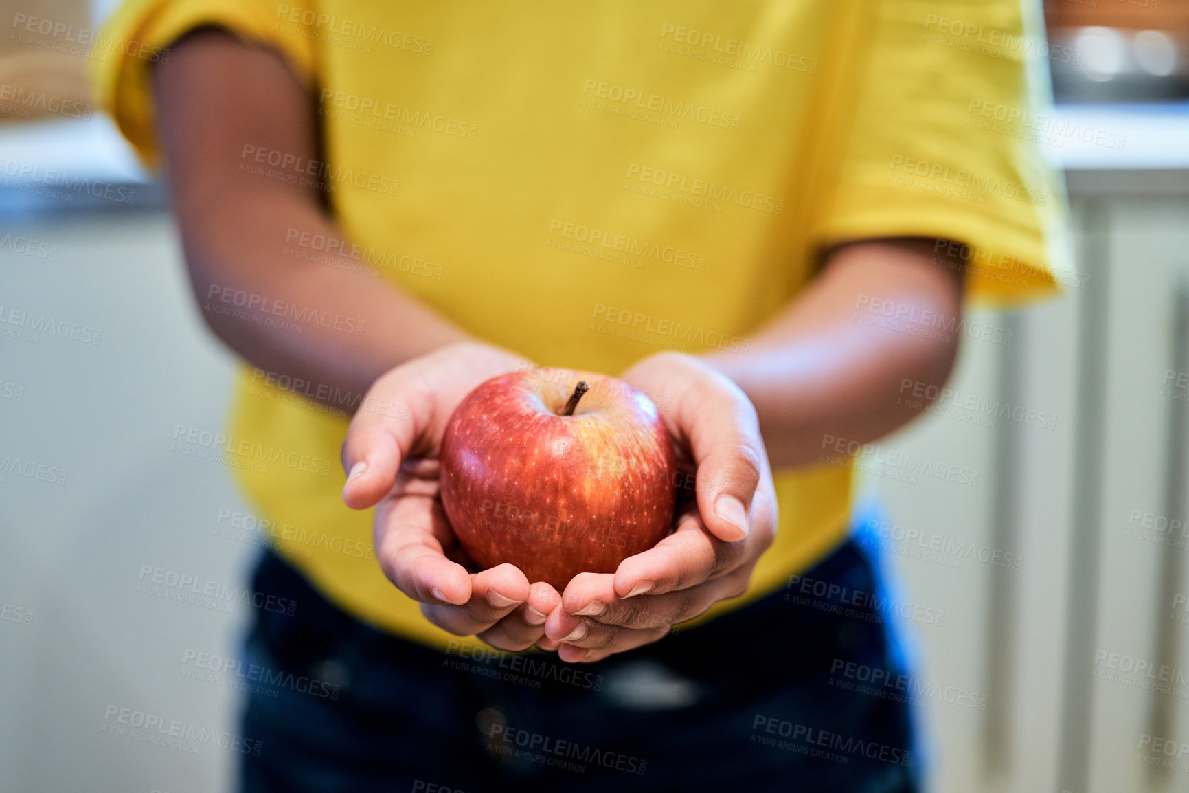 Buy stock photo Cropped shot of a boy holding an apple in his hands at home