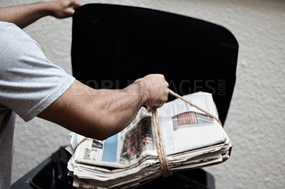 Buy stock photo Shot of a young man putting newspaper in the bin to be recycled