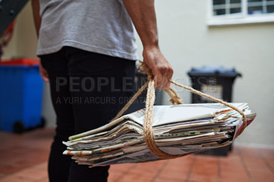 Buy stock photo Cropped shot of a unrecognizable man on his way to recycle newspaper at home