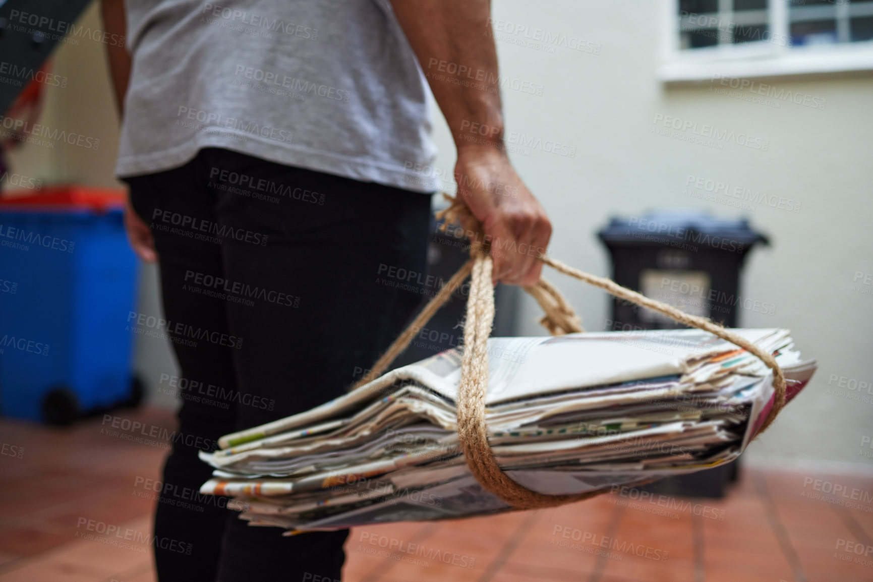 Buy stock photo Cropped shot of a unrecognizable man on his way to recycle newspaper at home