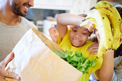 Buy stock photo Shot of a family unpacking the groceries in the kitchen at home