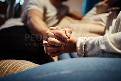 Buy stock photo Cropped shot of a young couple holding hands while sitting together at home