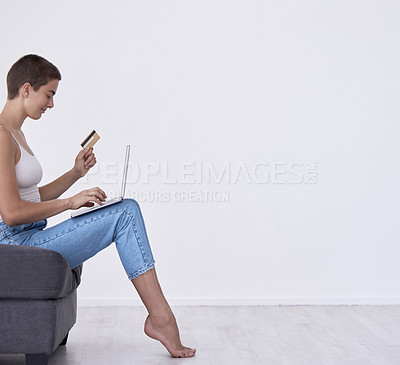 Buy stock photo Shot of a woman holding a credit card while using her laptop at home
