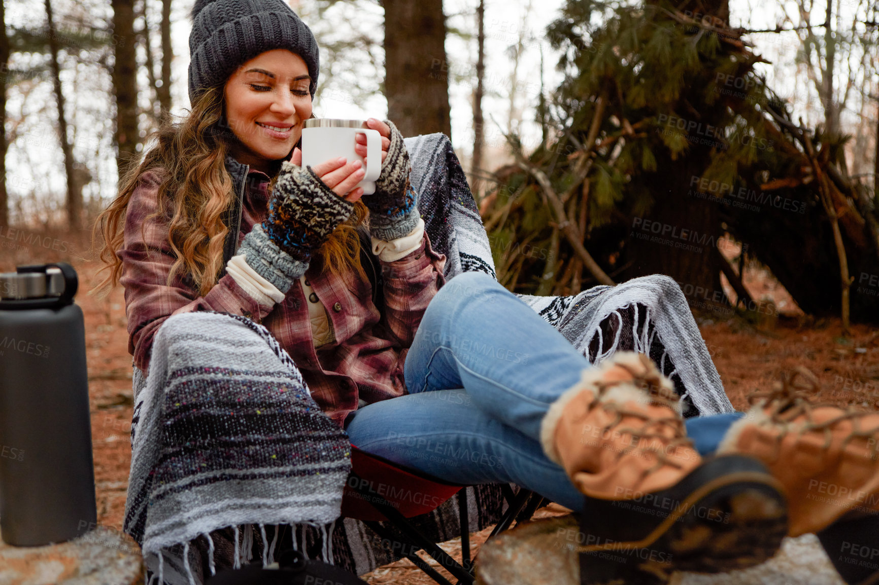 Buy stock photo Shot of a young woman drinking a warm beverage while camping in the wilderness during winter