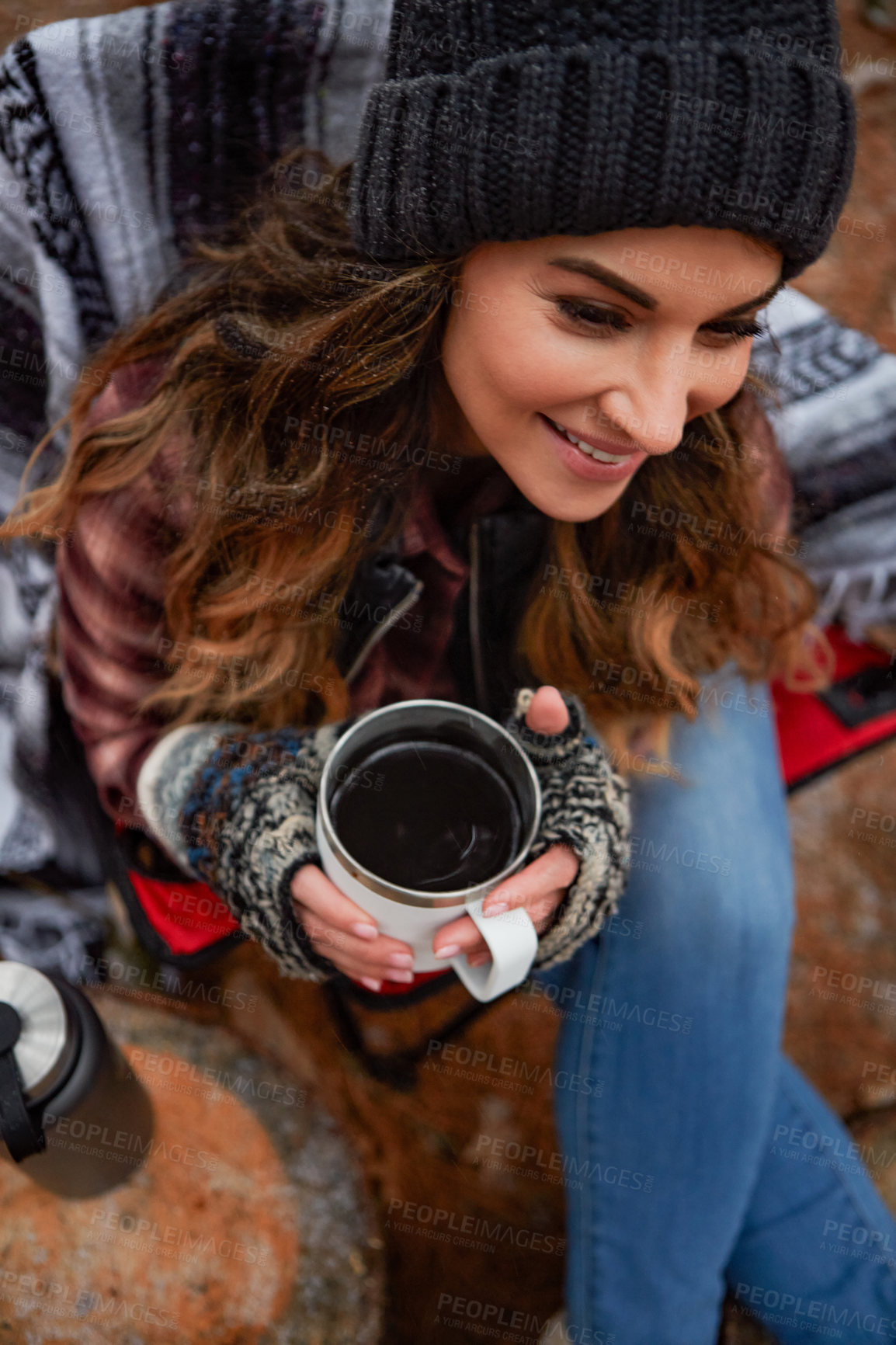 Buy stock photo High angle shot of a young woman drinking a warm beverage while camping in the wilderness during winter