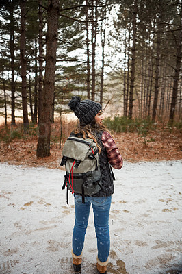 Buy stock photo Rearview shot of a young woman hiking in the wilderness during winter