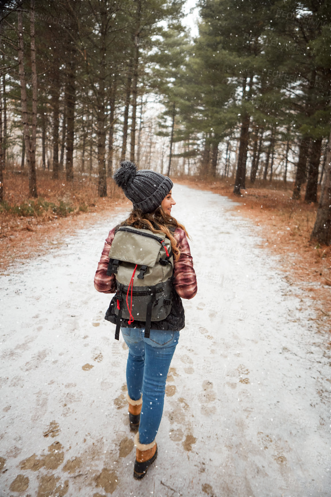 Buy stock photo Rearview shot of a young woman hiking in the wilderness during winter