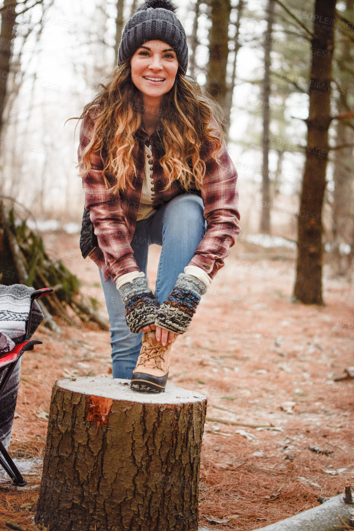 Buy stock photo Portrait of a young woman tying her shoelaces while camping in the wilderness during winter