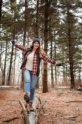 Buy stock photo Shot of a young woman walking on a tree log in the wilderness during winter