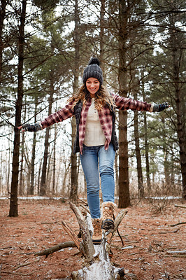 Buy stock photo Shot of a young woman walking on a tree log in the wilderness during winter