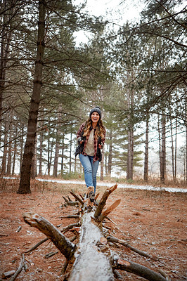 Buy stock photo Shot of a young woman walking on a tree log in the wilderness during winter
