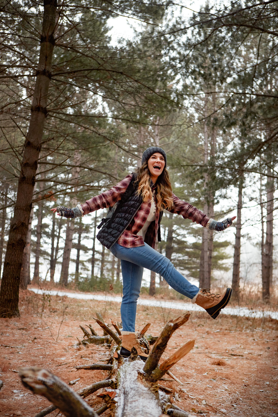 Buy stock photo Shot of a young woman walking on a tree log in the wilderness during winter