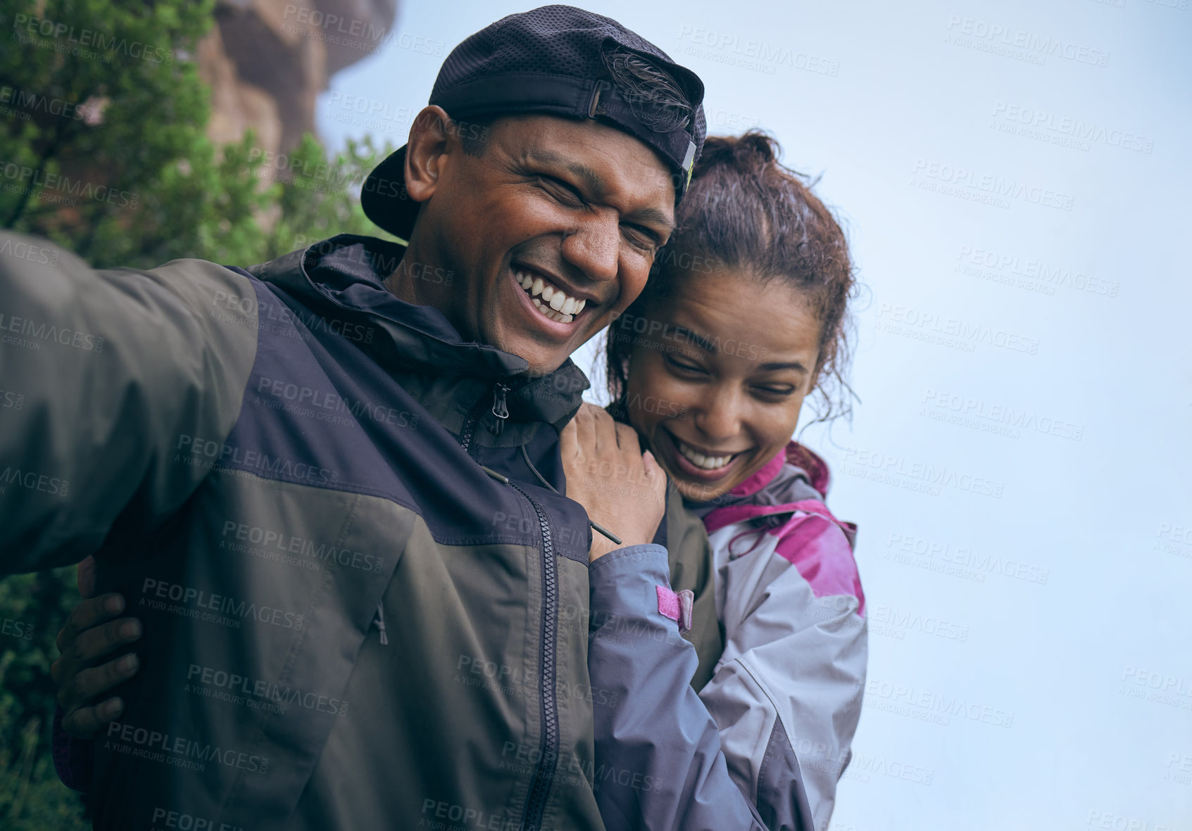 Buy stock photo Cropped shot of an affectionate young couple laughing while taking a selfie during their early morning hike