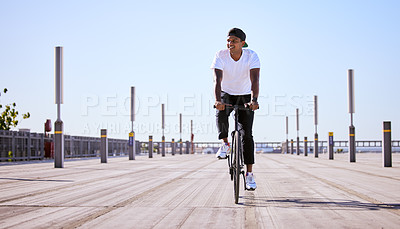 Buy stock photo Shot of a young man riding a bike on a sunny day.