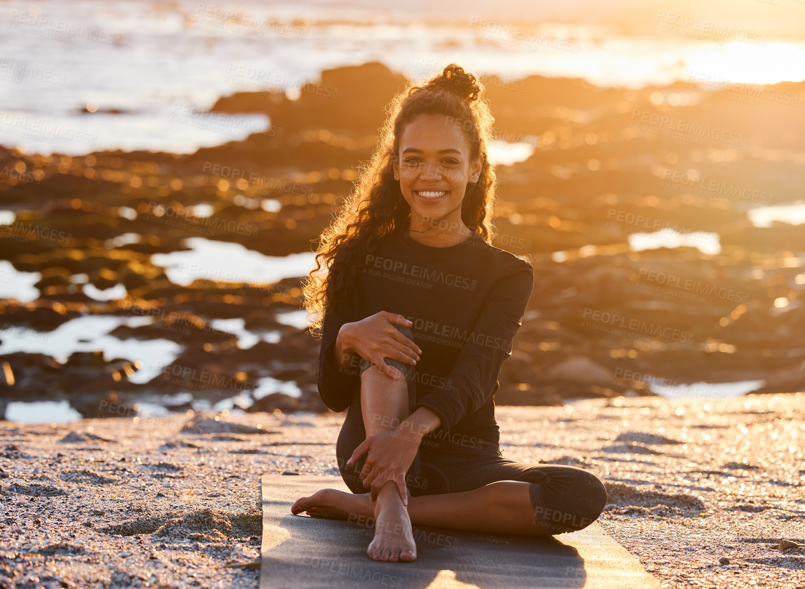 Buy stock photo Shot of an attractive young woman sitting on her yoga mat during a yoga session on the beach at sunset