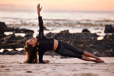 Buy stock photo Shot of an attractive young woman doing yoga alone on the beach at sunset