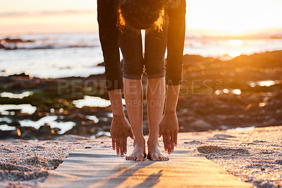 Buy stock photo Cropped shot of an unrecognizable woman doing yoga alone on the beach at sunset