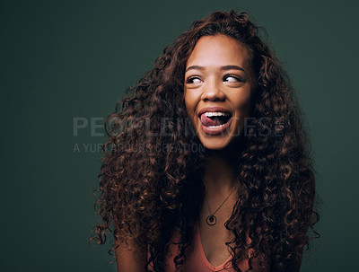 Buy stock photo Natural beauty, tongue out and happy gen z girl with hair, curly and curious on green background. Afro, wellness care and female model with fun, emoji and silly face, personality or comic in studio