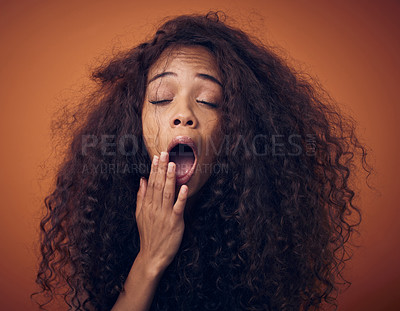 Buy stock photo Shot of a young woman with curly hair yawning against an orange background