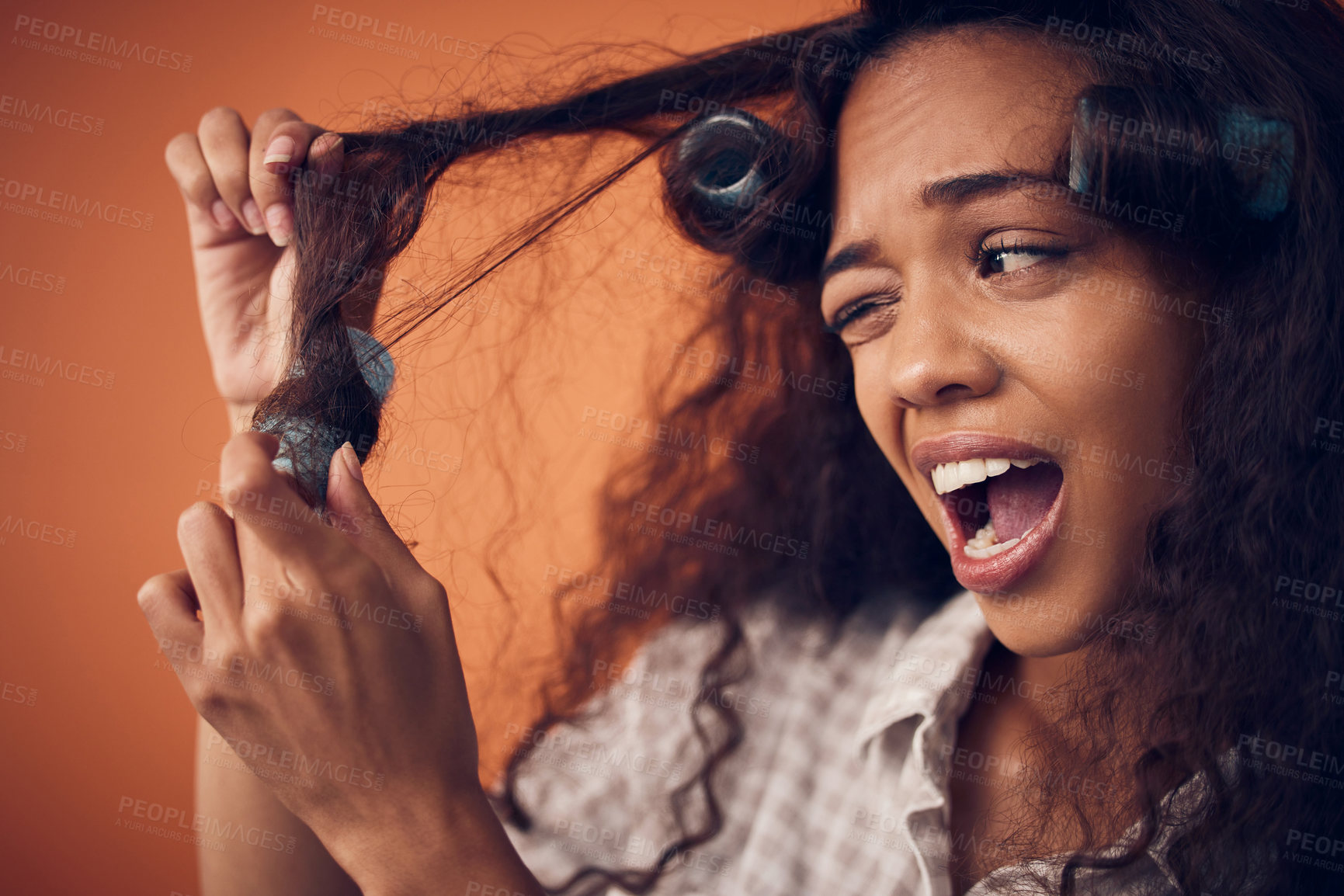 Buy stock photo Shot of a woman pulling hair rollers out of her hair